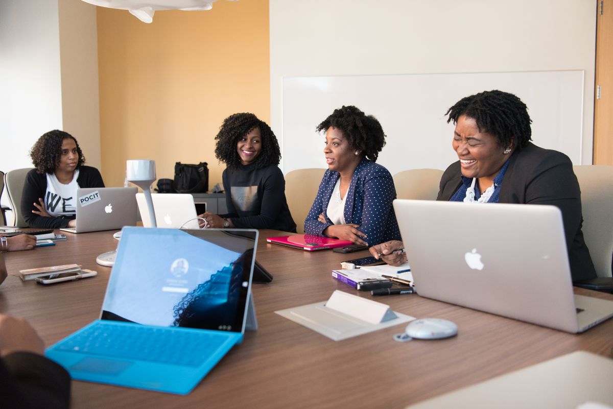 Colleagues working together around a conference table with laptops, smiling during a planning discussion